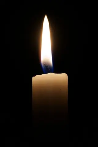 Eine Kerze vor schwarzem Grund leuchtet ins Dunkel