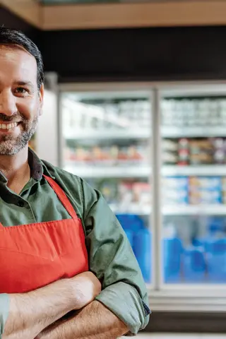 Ein männlicher Verkäufer vor Gemüseregal im Bio-Supermarkt