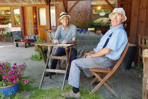 Dieter und Jochen Scharmer sitzen vor dem Hofladen auf Hof Dannwisch 