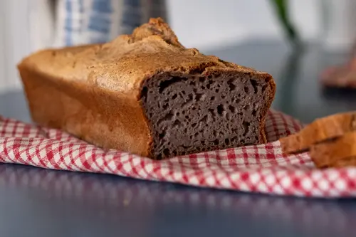 Buchweizenbrot aufgeschnitten, liegend auf rotkariertem Handtuch vor einer Wasserkaraffe
